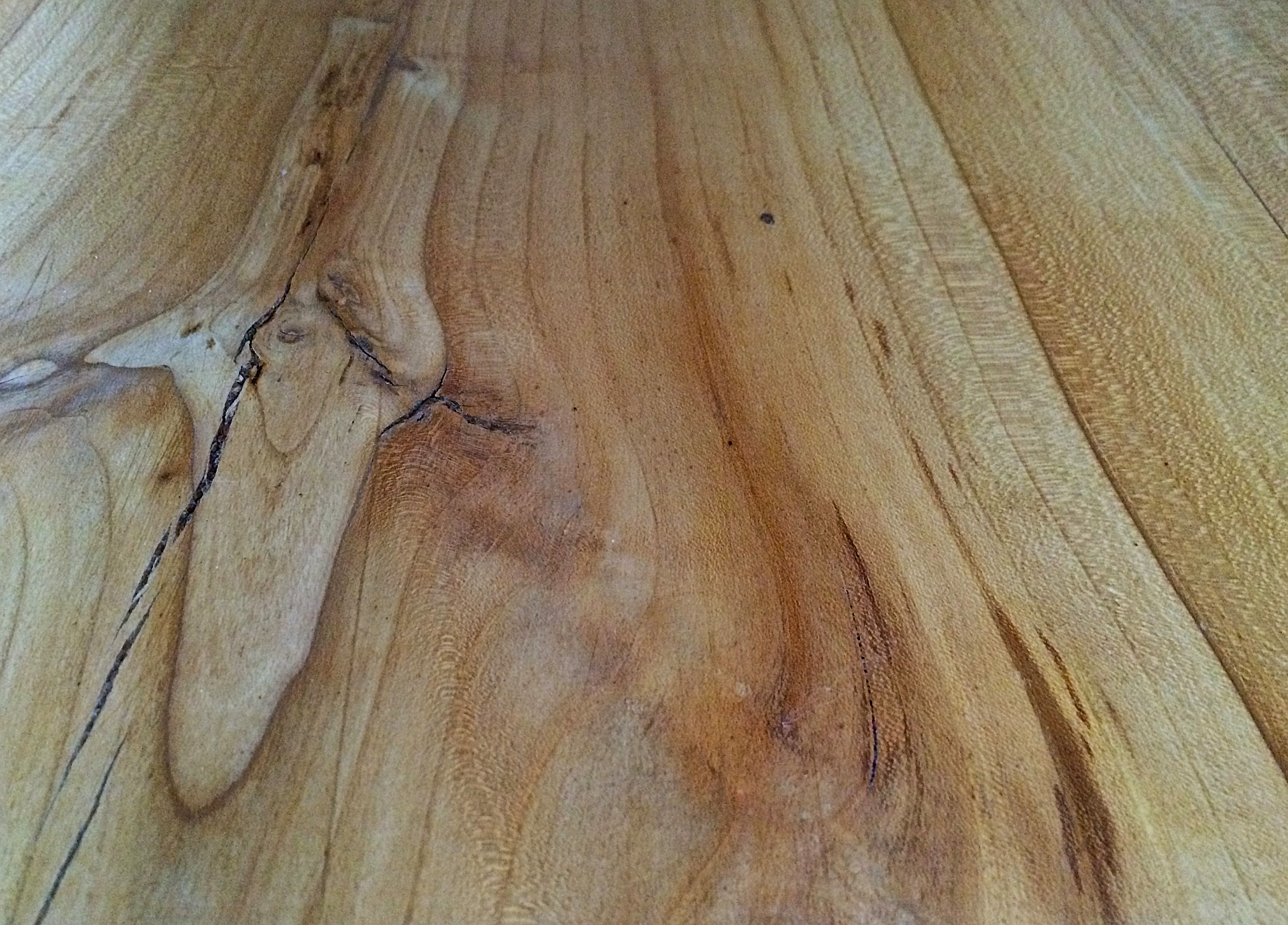 Nahaufnahme einer Holzoberfläche mit sichtbarer Maserung und leichten Verfärbungen.