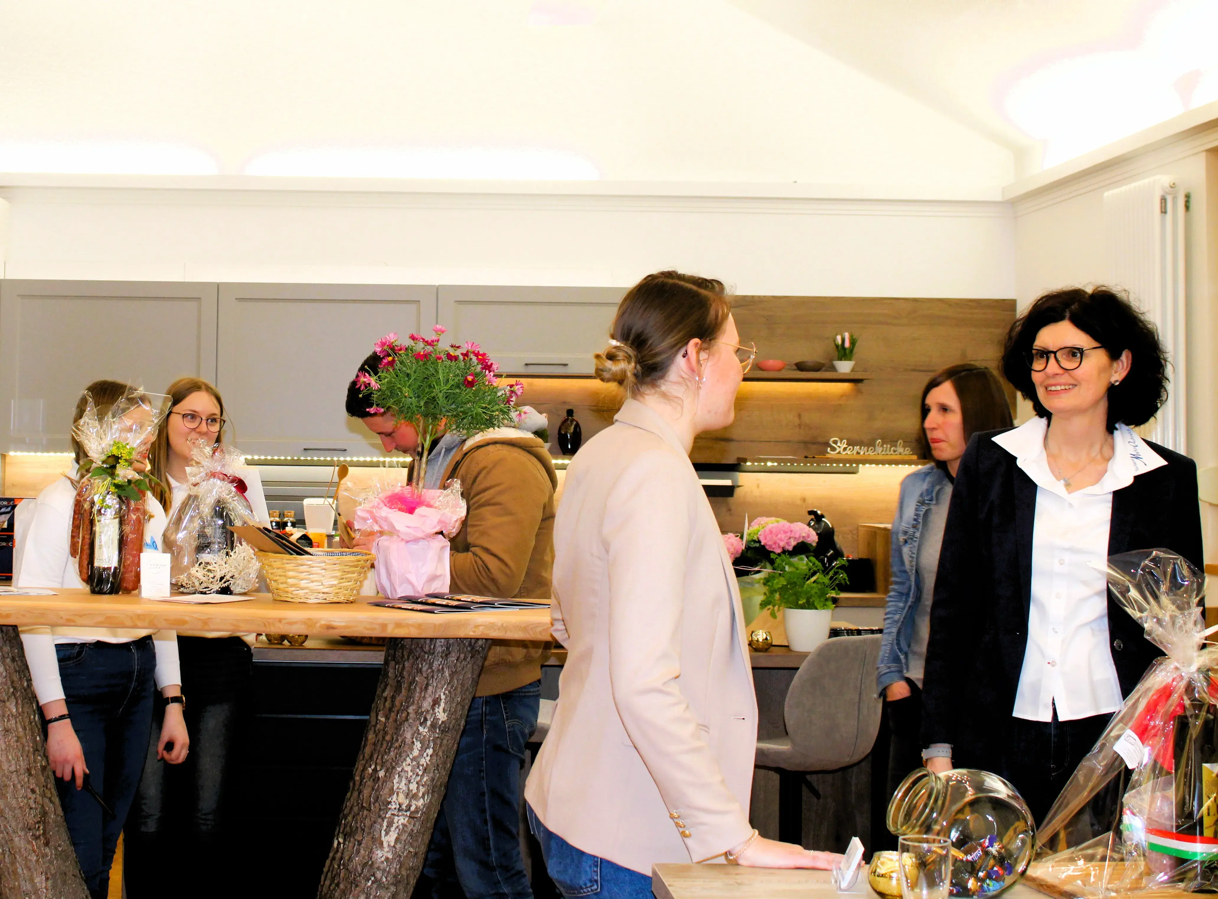 Menschen unterhalten sich in einer modernen Küche mit Blumen und Dekorationen.