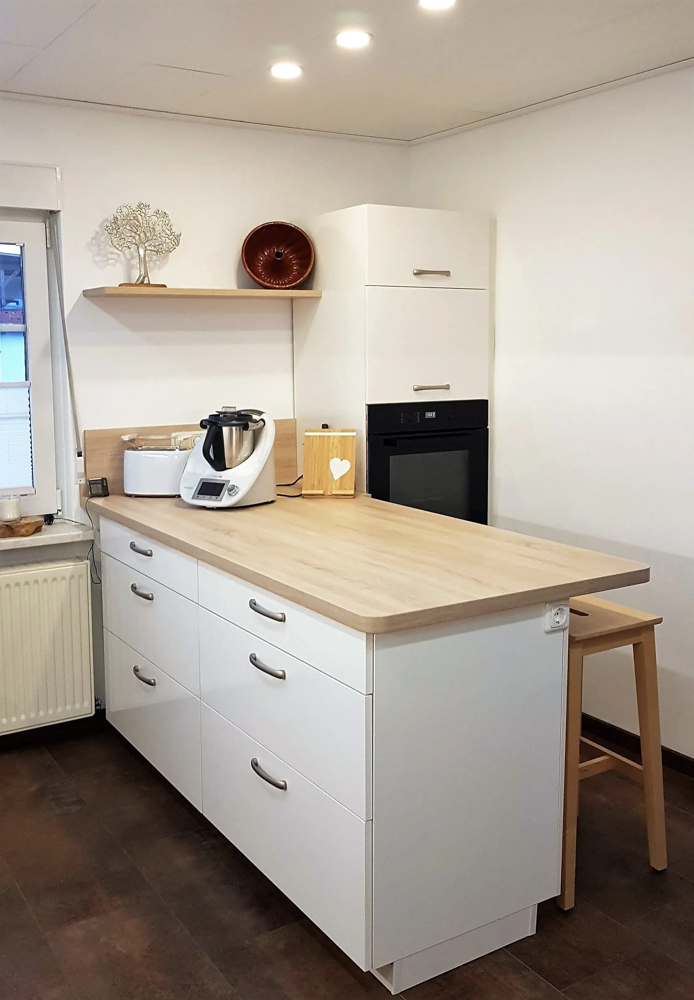 Moderne weiße Küche mit Kochinsel, Ofen, Küchenmaschine und Barhocker