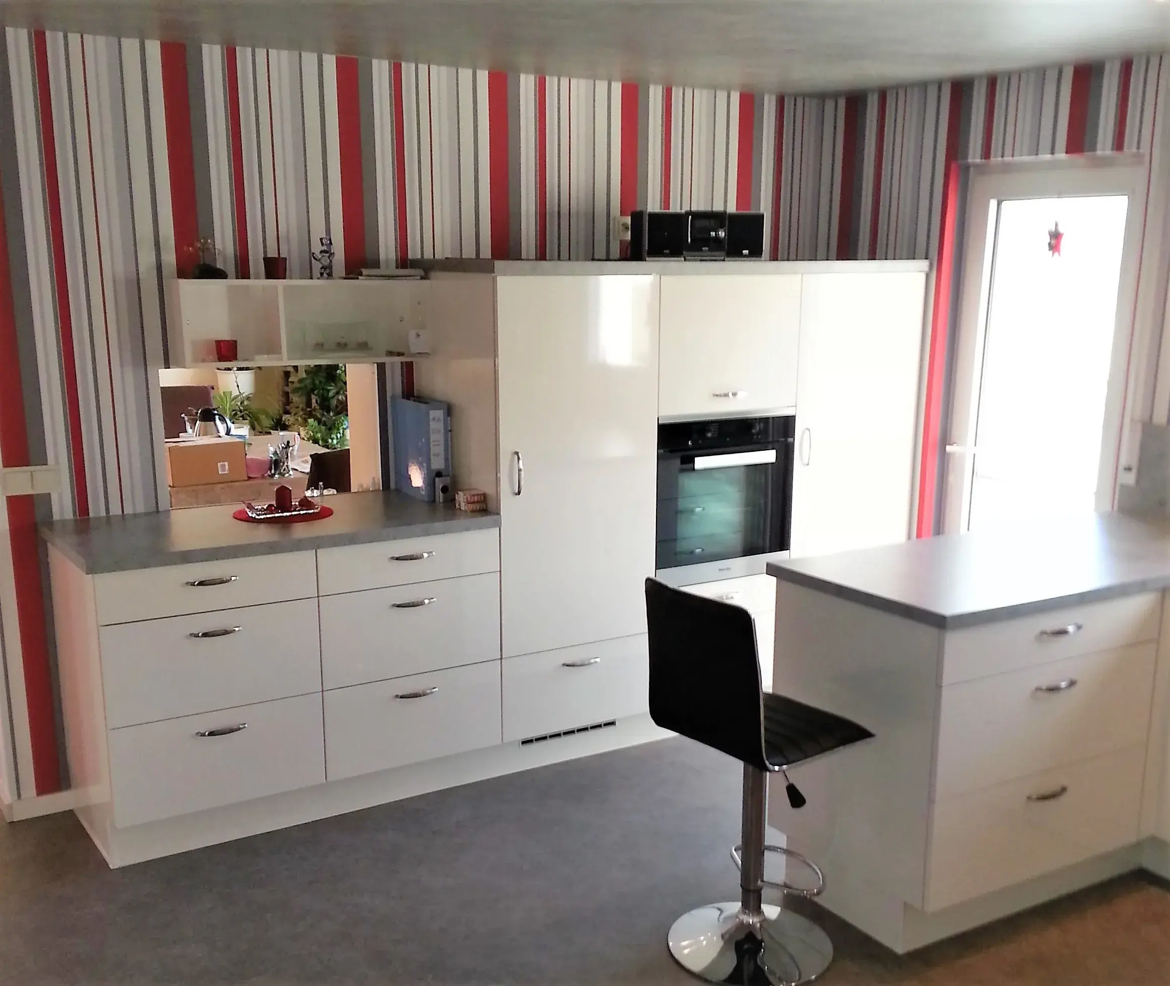 Moderne weiße Küche mit Hochglanzschränken und gestreifter Tapete in Rot und Grau.