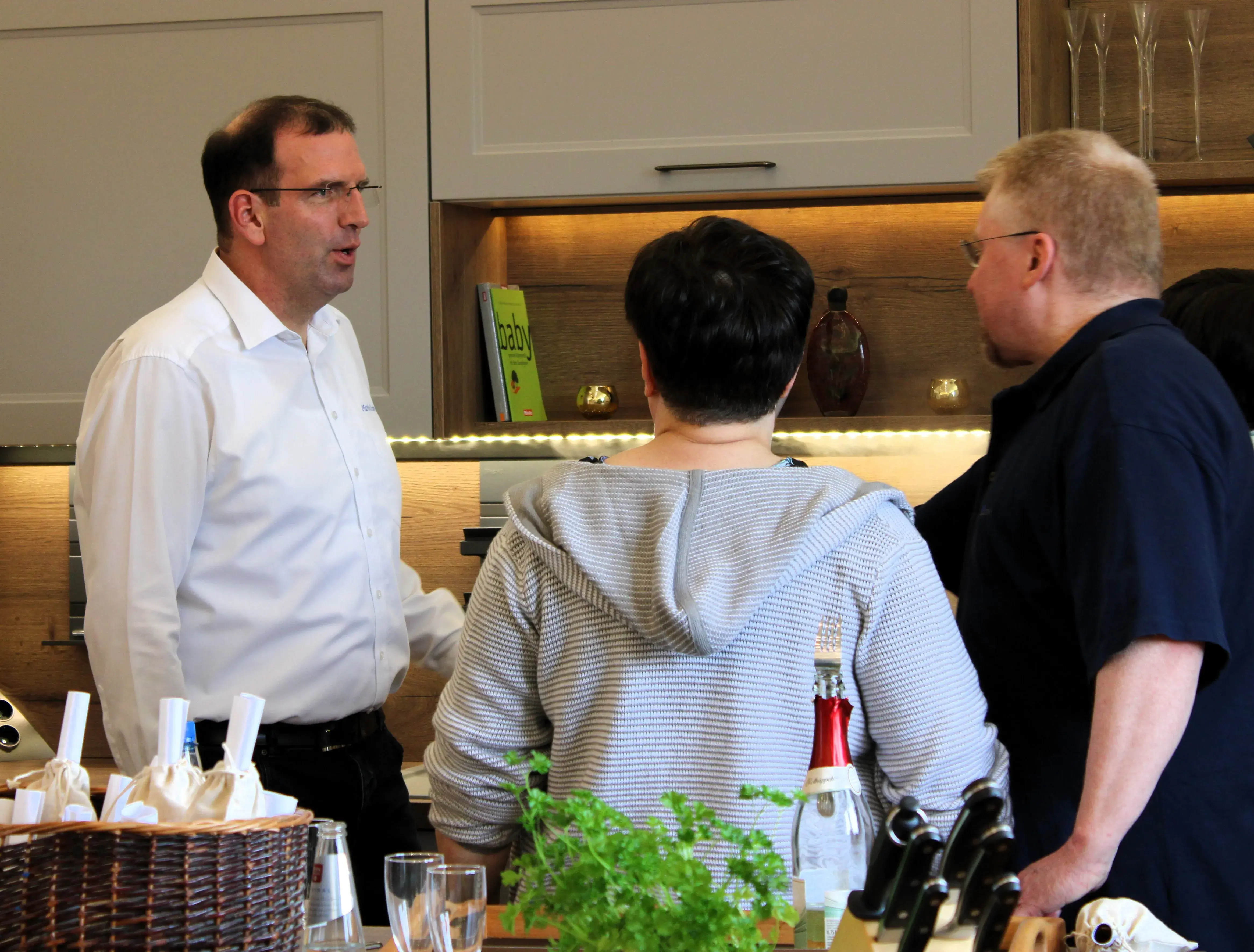 Drei Personen unterhalten sich in einer modernen Küche.