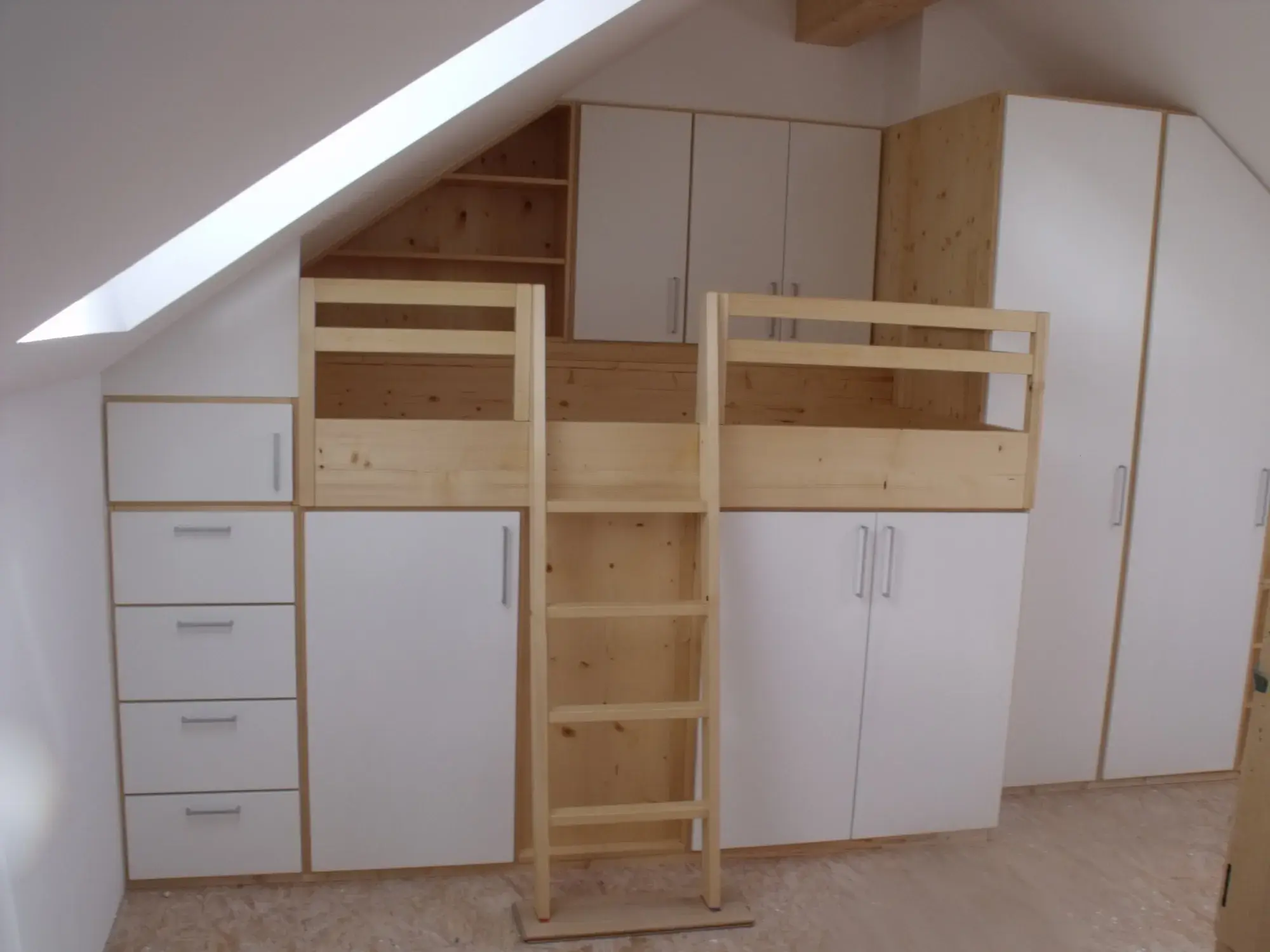 Hochbett aus Holz mit Einbauschränken und Schubladen unter einer Dachschräge.