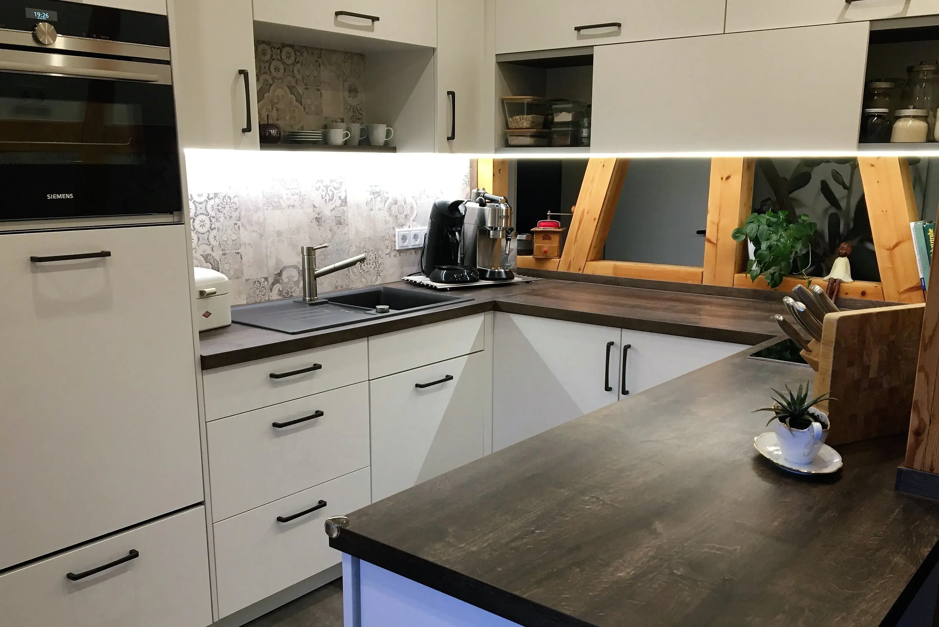 Moderne Küche mit weißen Schränken, Holzarbeitsplatte und Geräten auf der Theke.