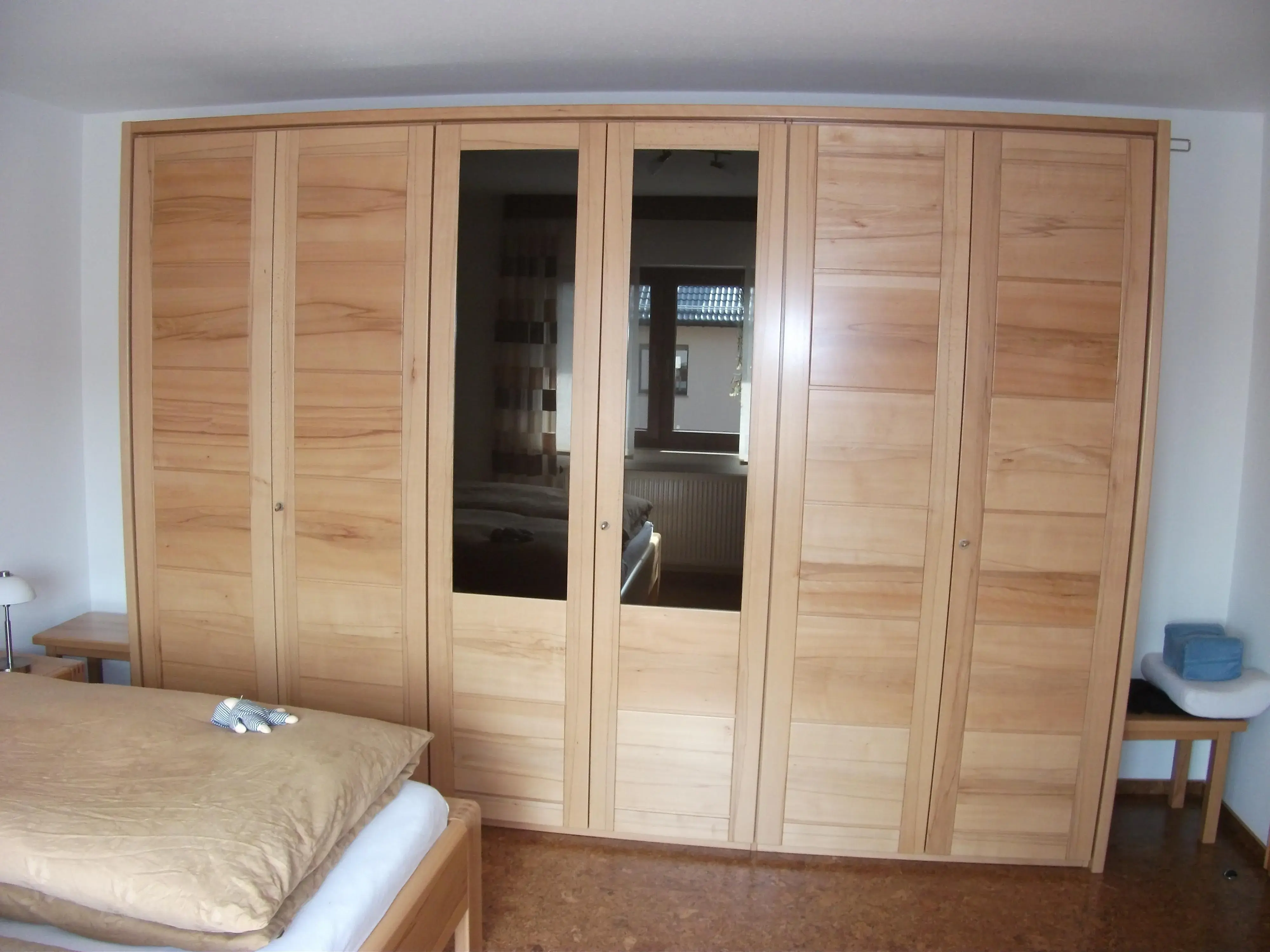 Großer Kleiderschrank aus Holz mit Spiegeltüren in einem Schlafzimmer.
