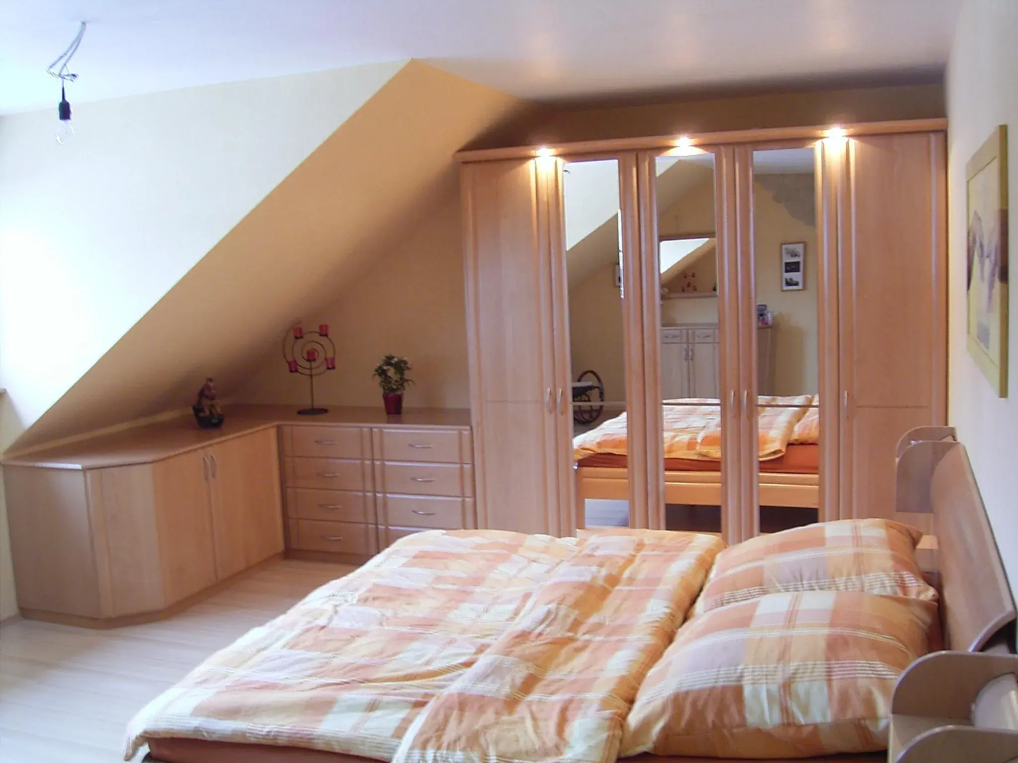 Helles Schlafzimmer mit Dachschräge, Doppelbett und großem Spiegelschrank.
