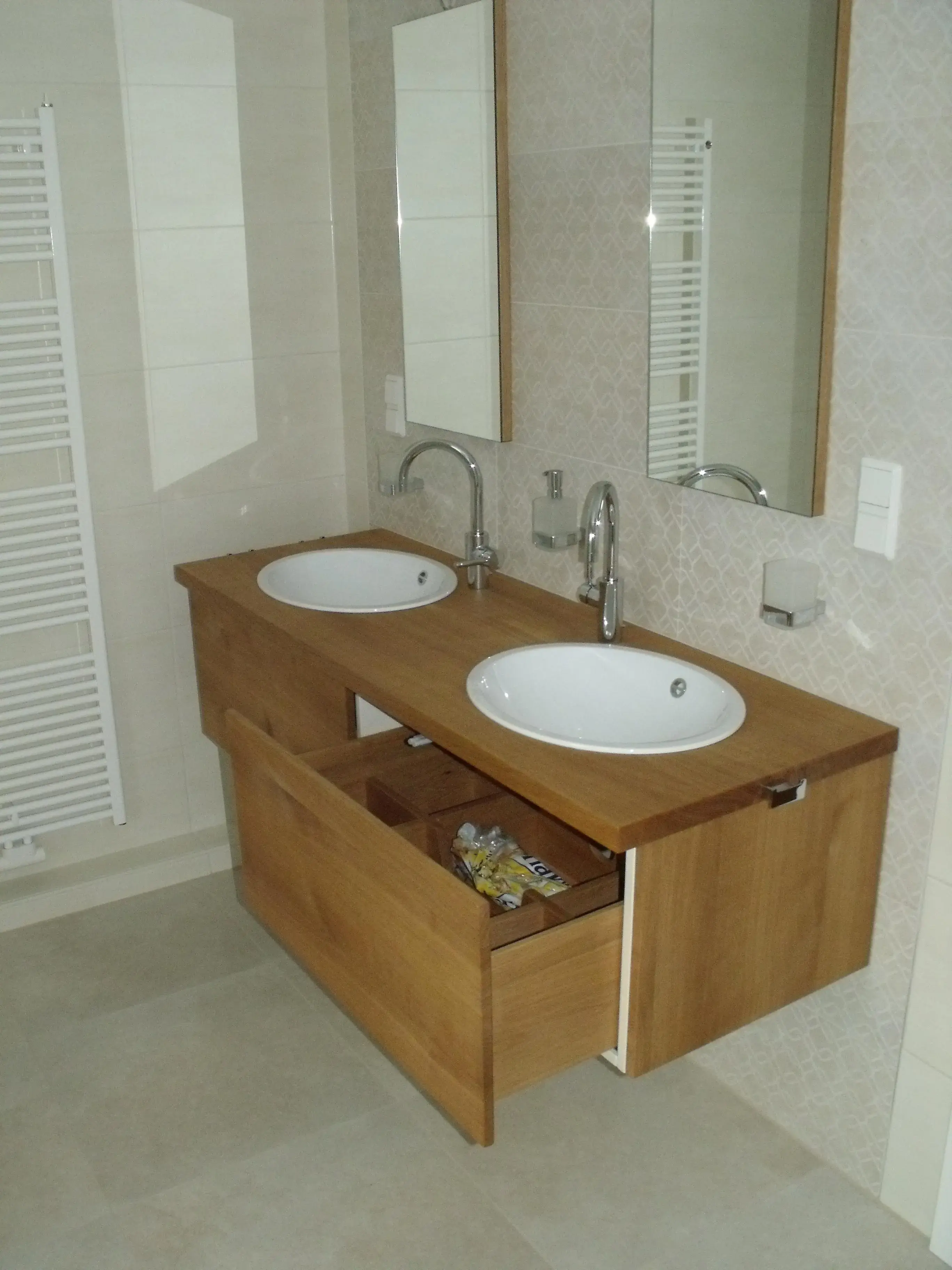 Doppelwaschtisch aus Holz mit zwei weißen Waschbecken und offenen Schubladen.