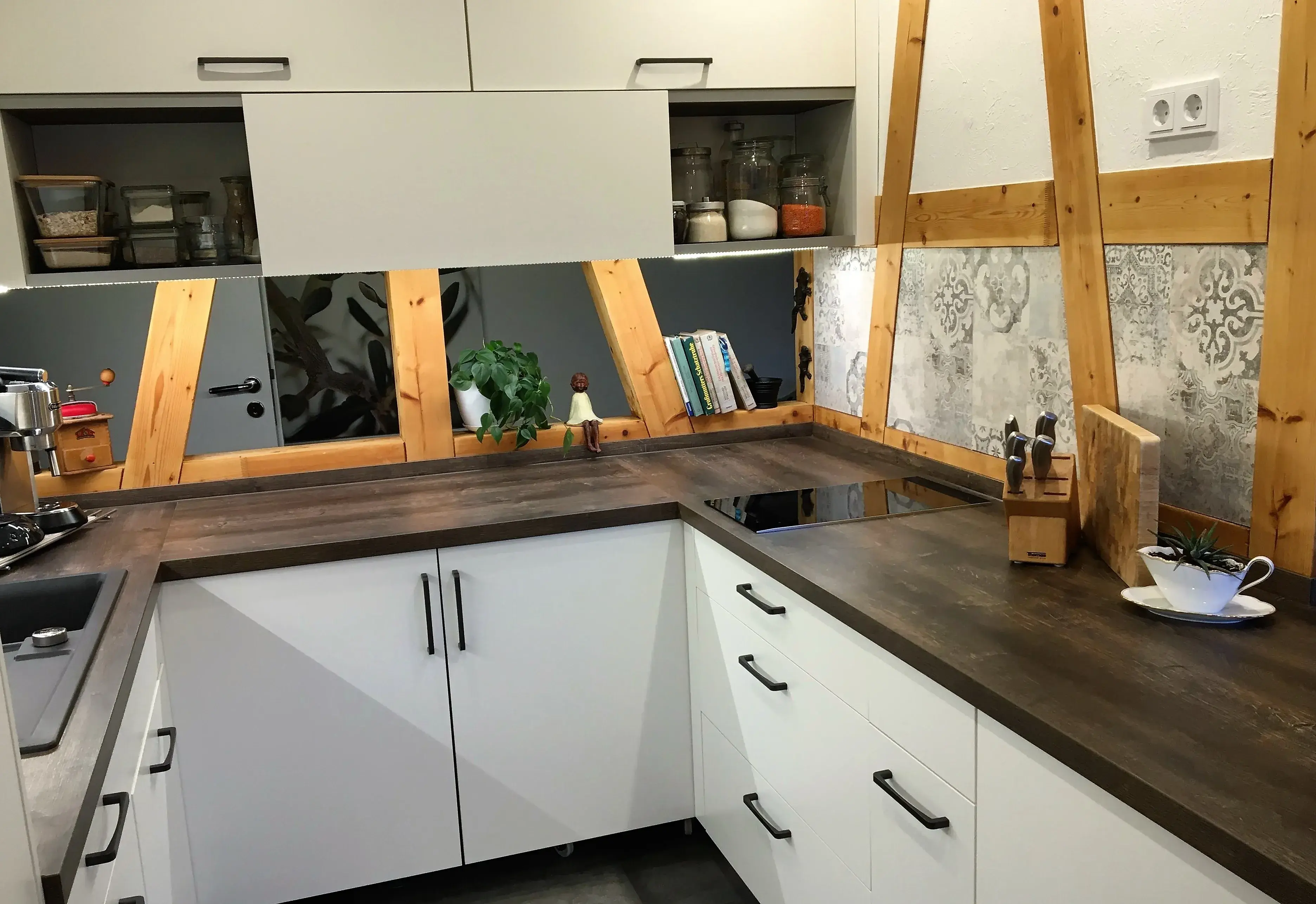 Moderne Küche mit Holzdetails, weißen Schränken und dunkler Arbeitsplatte.