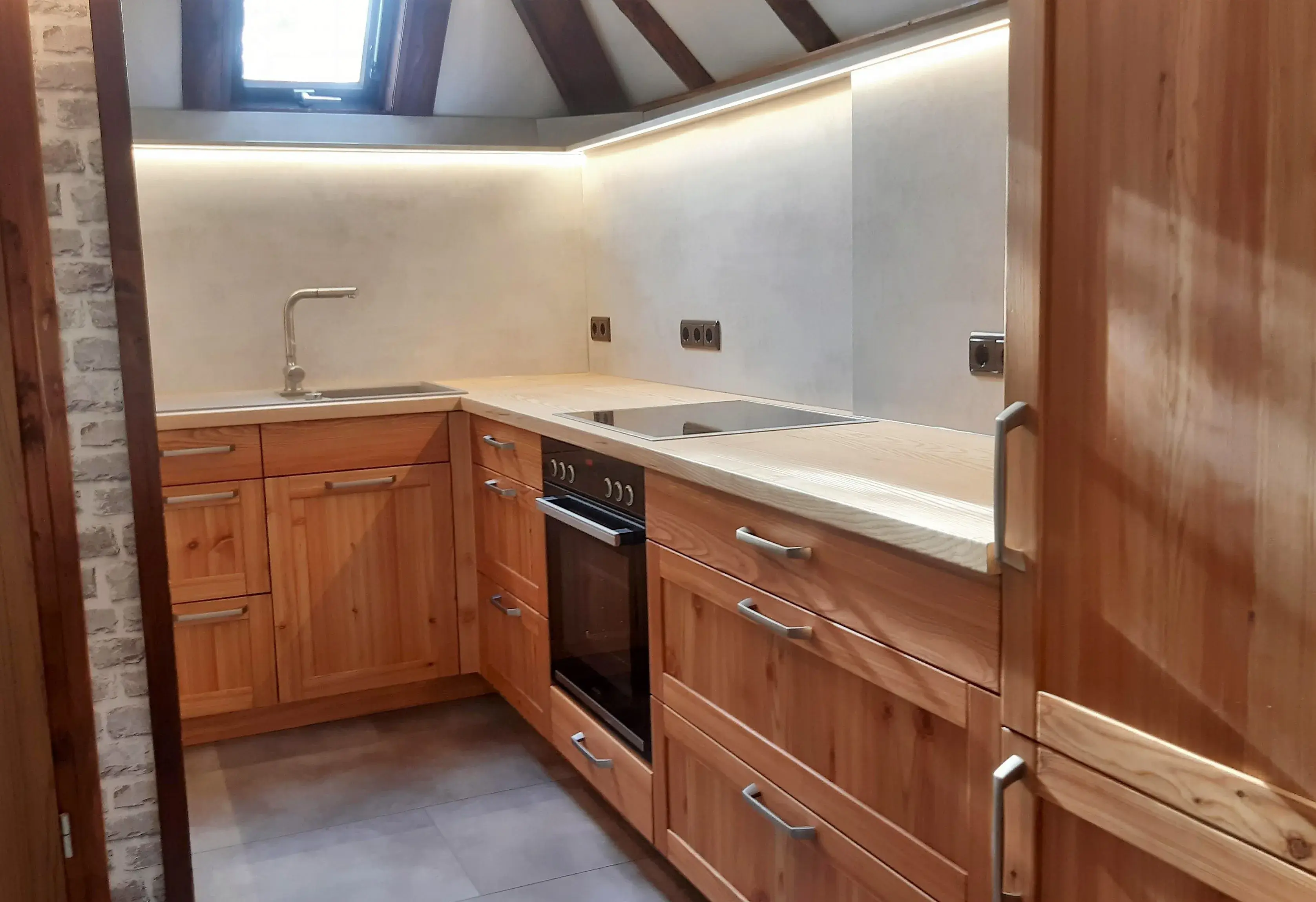 Gemütliche Küche mit Holzfronten, Induktionsherd, Backofen und Oberlicht.