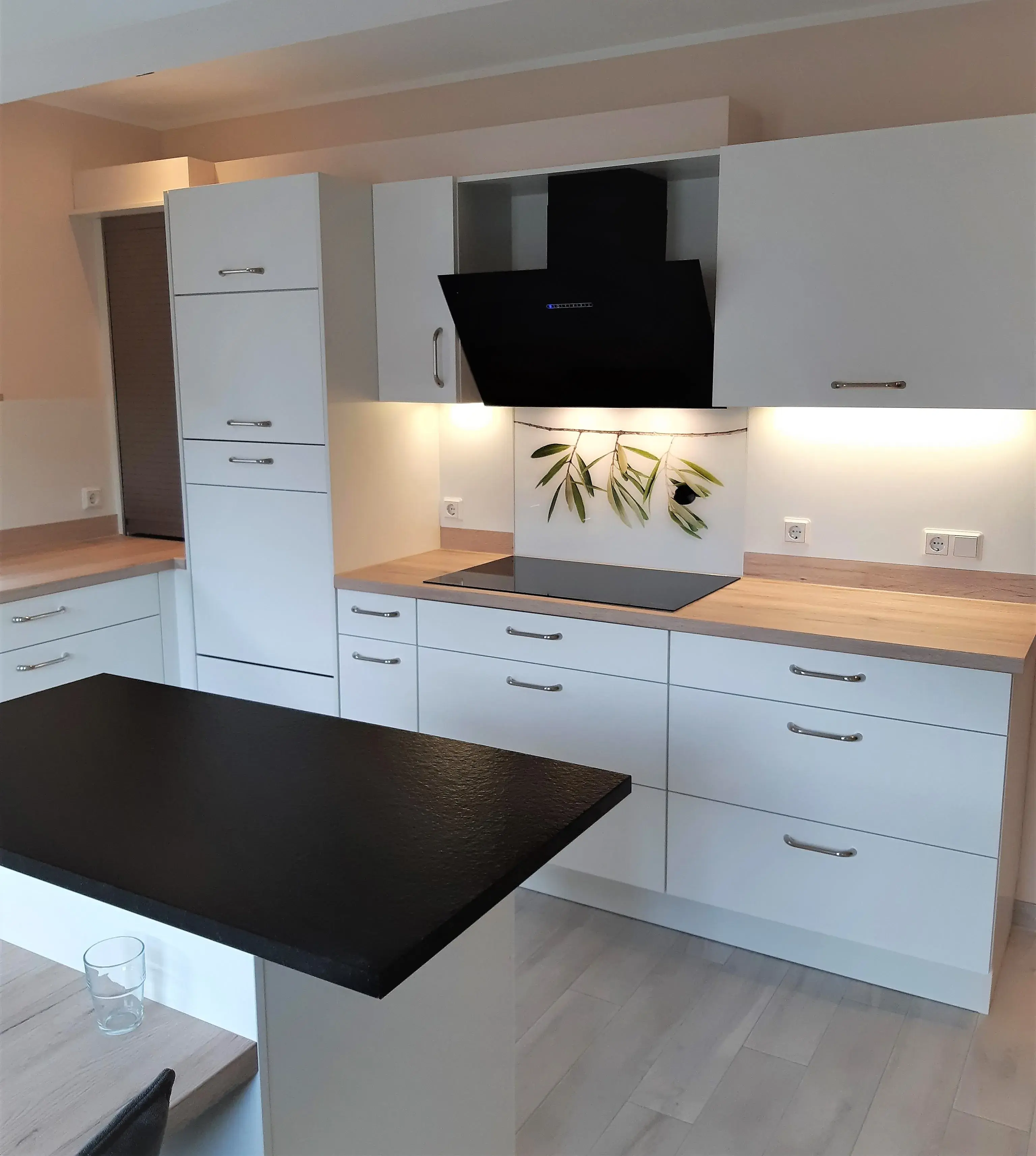 Moderne helle Küche mit Holzarbeitsplatten und schwarzer Dunstabzugshaube.